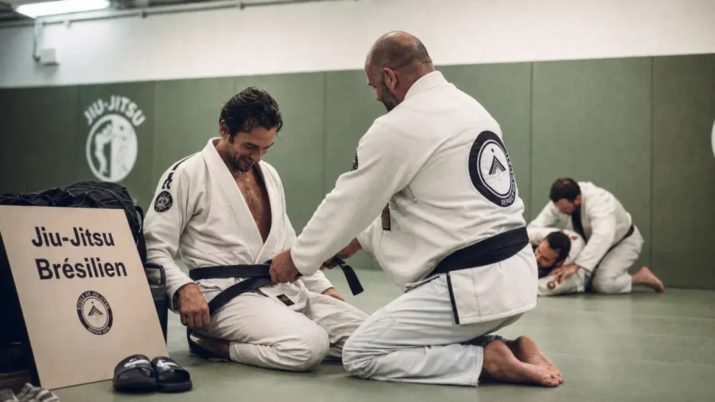 Club jiu jitsu bresilien : coach ajuste la ceinture, dojo et essai